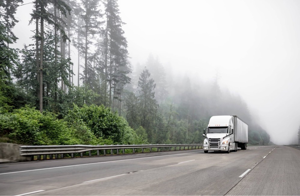 Semi truck rolling through mountain fog at speed
